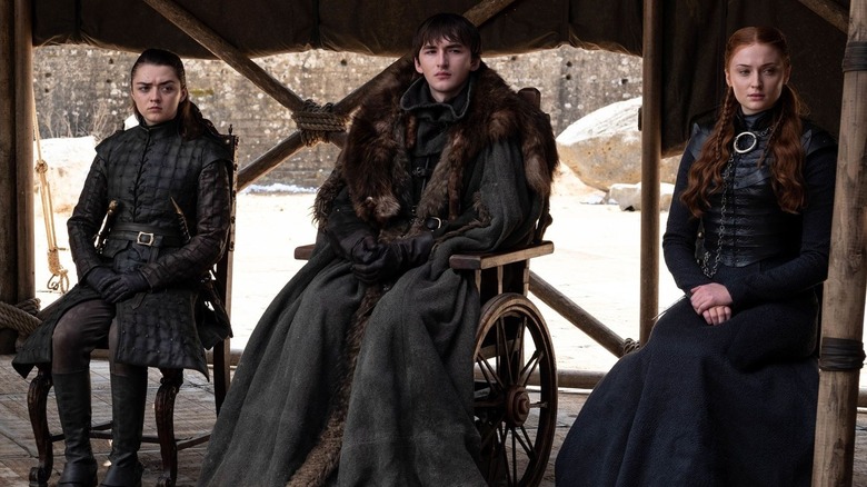 Arya Stark (Maisie Williams), Bran Stark (Isaac Hempstead Wright), and Sansa Stark (Sophie Turner) sit expectantly in Game of Thrones