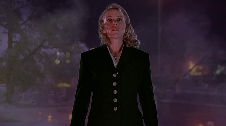 Frances McDormand as Julie looking up as rubble burns behind her in Darkman