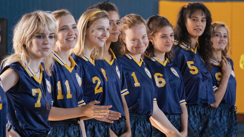 the girls from the show yellowjackets lined up in uniform smiling