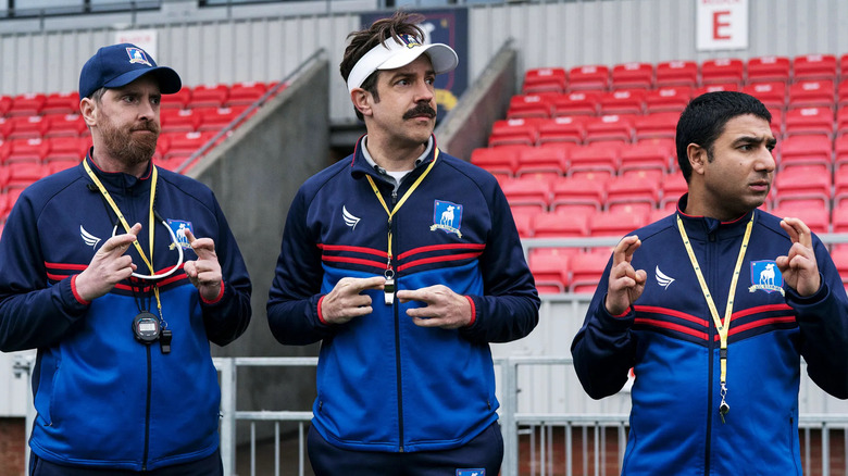 coach beard, ted lasso, and nate crossing their fingers in uniform on the sidelines