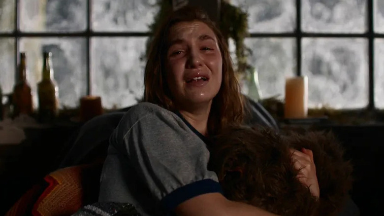 Inside the rustic wilderness cabin, Shauna (Sophie Nélisse) clutches a fur baby blanket and sobs while looking toward the camera in Yellowjackets
