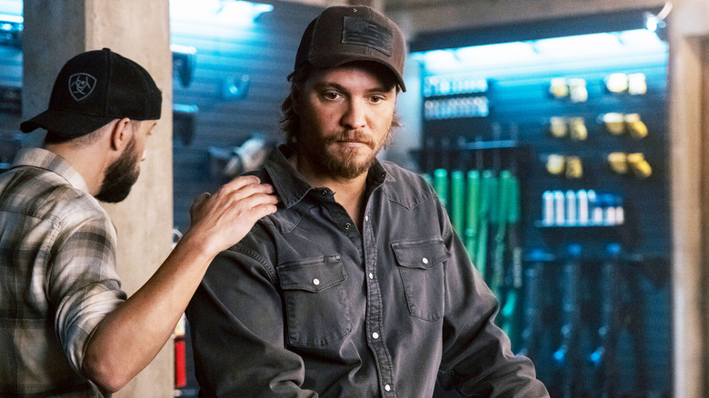 Luke Grimes' Kayce Dutton stands in an armory as Logan Marshall-Green puts his hand on his shoulder in Marshals