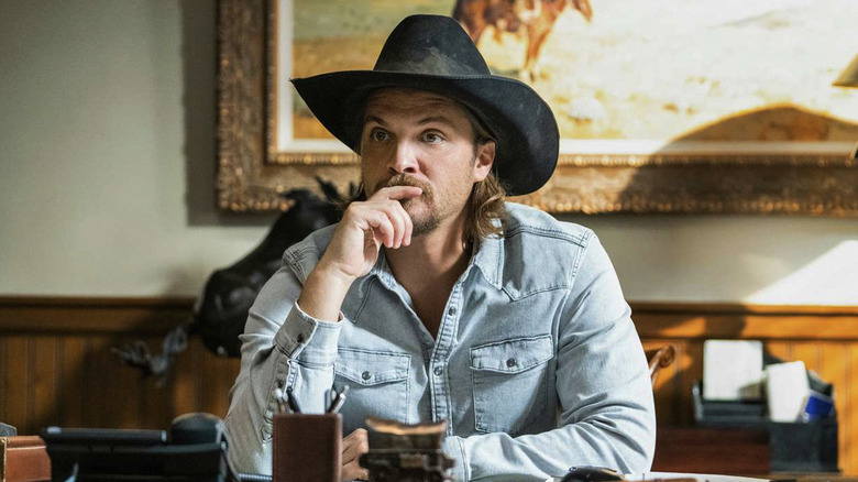Luke Grimes' Kayce Dutton is sitting at a desk on Yellowstone