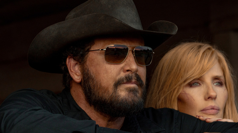 Cole Hauser's Rip Wheeler looks off into the distance wearing shades next to Kelly Reilly's Beth Dutton in Dutton Ranch