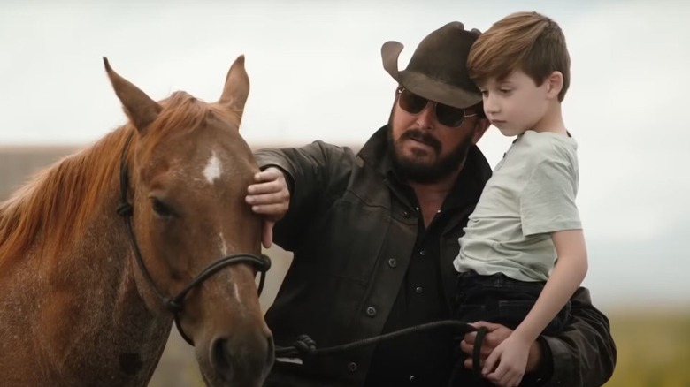 Rip Wheeler holding a child and applauding a horse on Yellowstone
