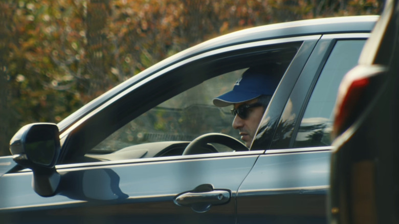 Nathan Fielder sitting in a car watching Elizabeth Holmes being escorted into prison in You Can See Everything