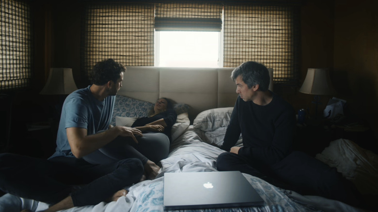 Billy Evans, Elizabeth Holmes, and Nathan Fielder sitting in a bed with a closed laptop in You Can See Everything