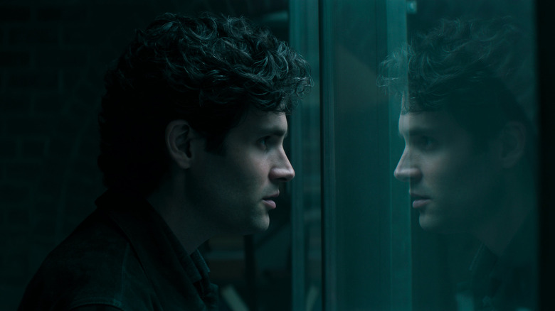 Joe Goldberg looking at his own reflection in his plastic cage in You