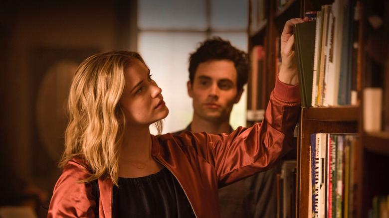 Guinevere Beck looks at books while Joe Goldberg looks at Guinevere Beck in You