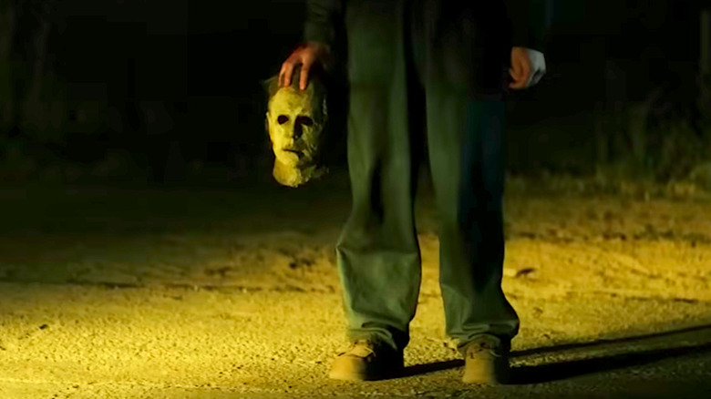 Michael Myers stands holding his mask in Halloween Ends