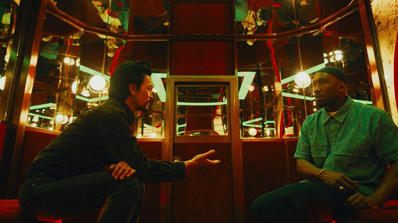John Cho as Hwan Yoon holding out his hand to Mahershala Ali as Latif in a private room full of mirrors in Your Mother Your Mother Your Mother