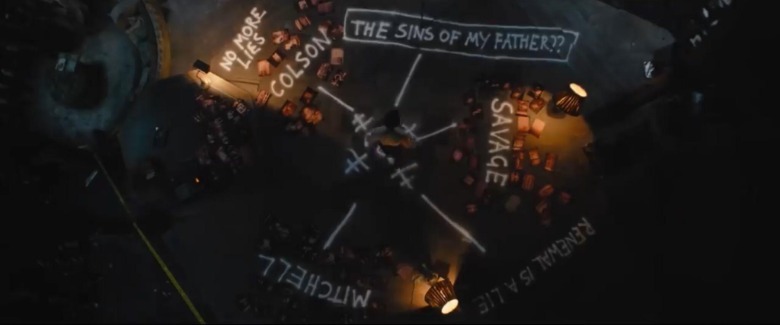 The Batman Bruce Wayne standing above Riddler mystery board